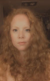 A woman in a filter photo with curly red hair, she is fair skinned